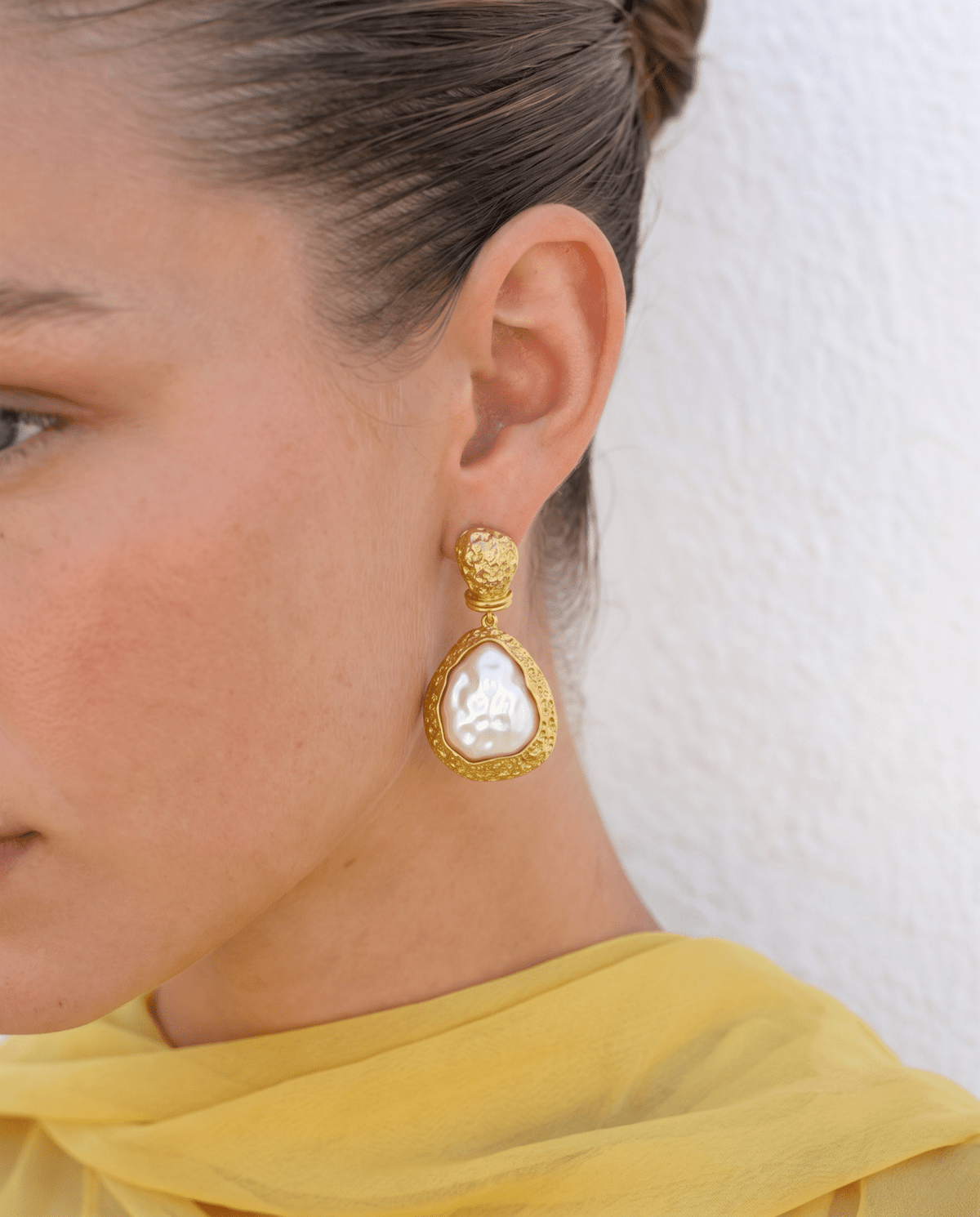 Faux pearl drop earrings worn on the ear