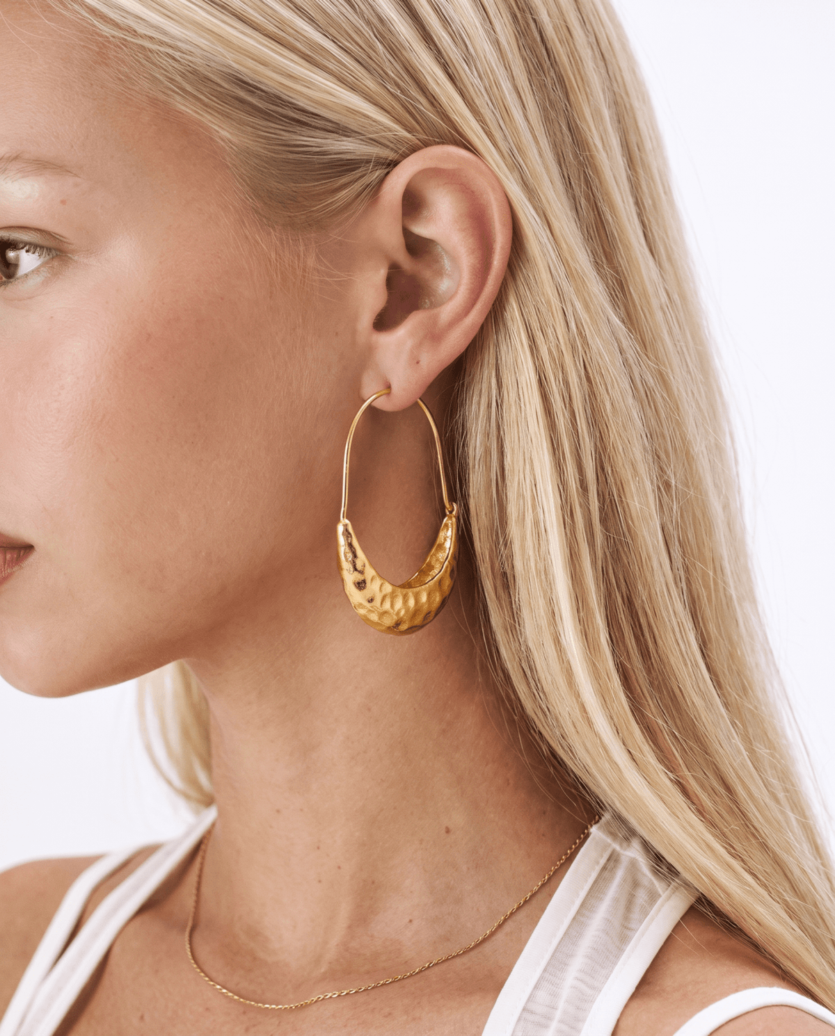 Gold crescent hoop earrings worn on the ear