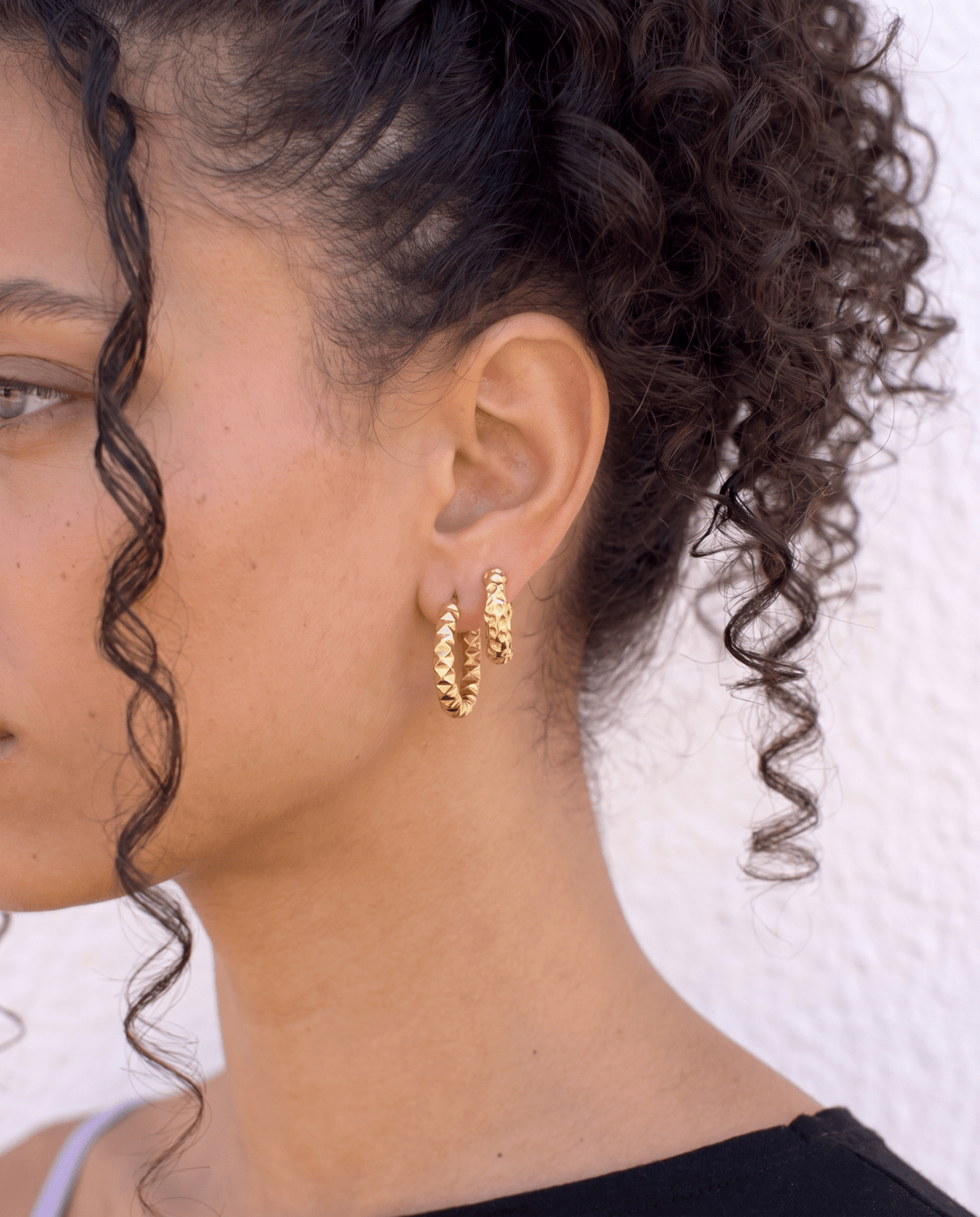 Small gold hoop earrings worn on the ear