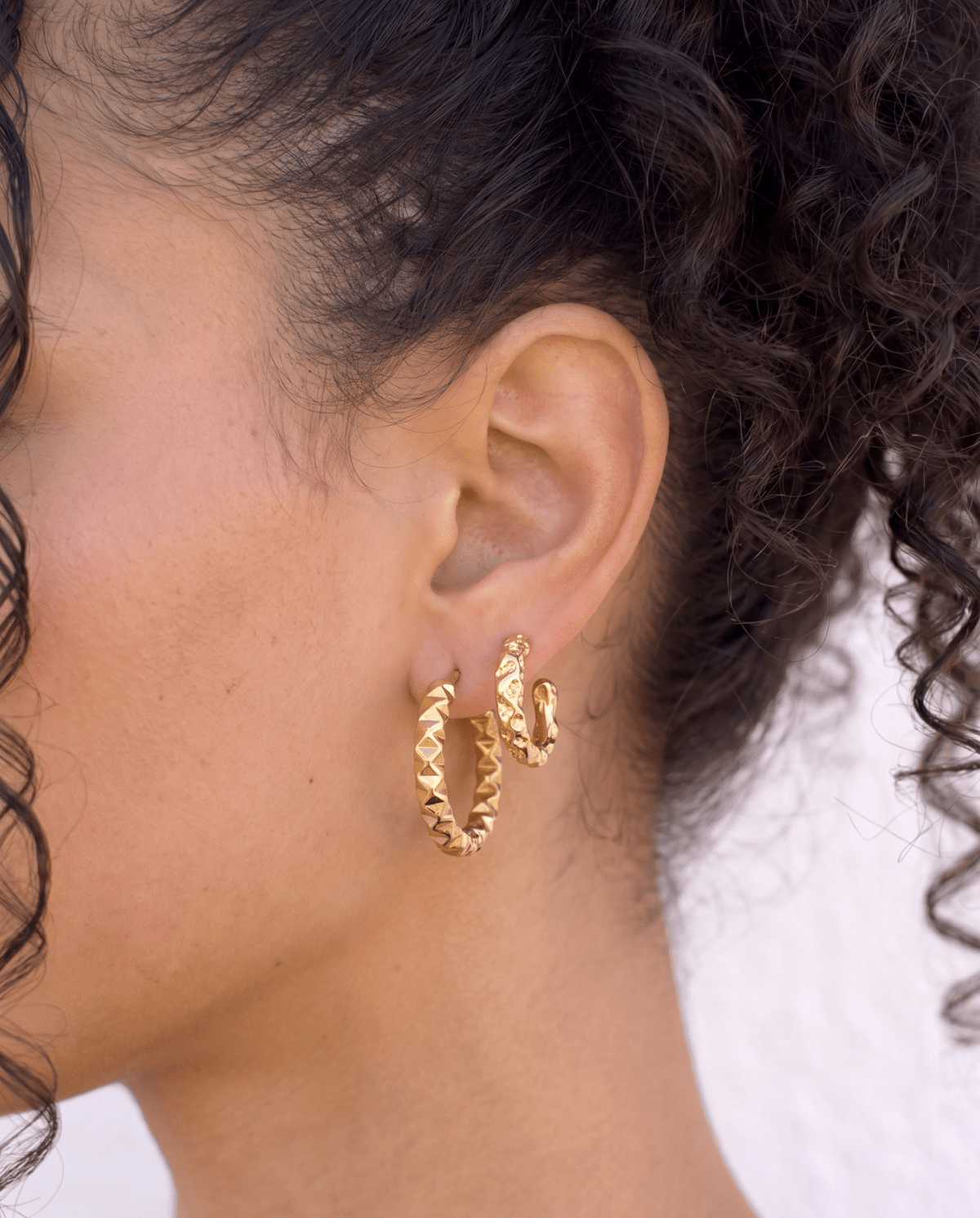 Small gold hoop earrings faceted side view on model