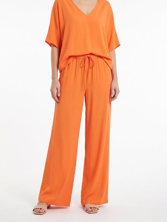 Orange V-neck top and wide-leg pants set on a white background