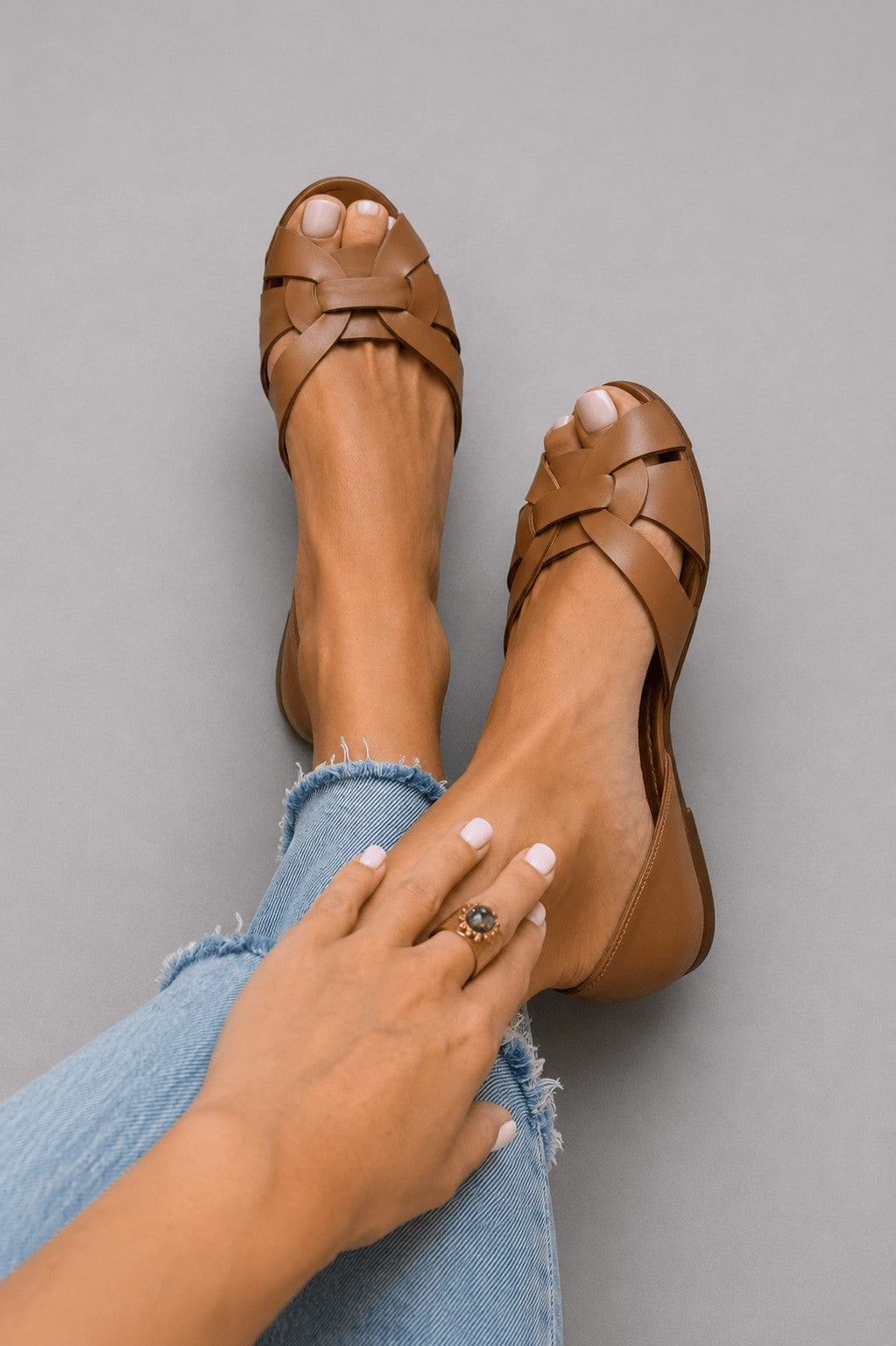 Woven cross-strap flat sandals in brown – worn